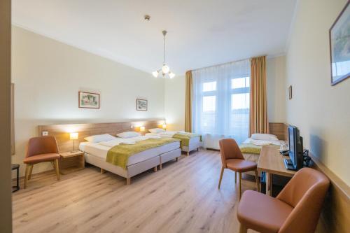 ein Hotelzimmer mit 3 Betten sowie einem Tisch und Stühlen in der Unterkunft Baross City Hotel - Budapest in Budapest