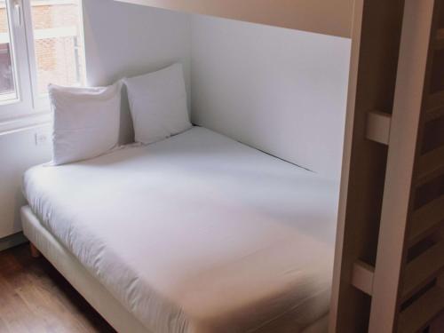 1 cama con sábanas blancas y almohadas en una habitación en greet hotel Lille Gare Flandres - Groupe Accor, en Lille