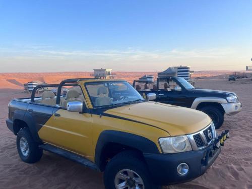 two trucks parked in the sand in the desert at Oman desert private camp in Shāhiq