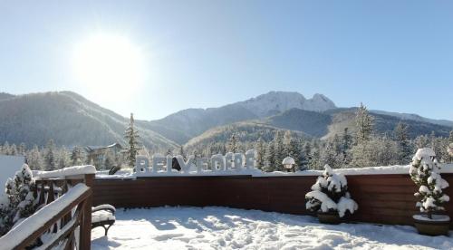 un balcone coperto da neve con un cartello con le montagne sullo sfondo di Hotel Belvedere Resort&SPA a Zakopane