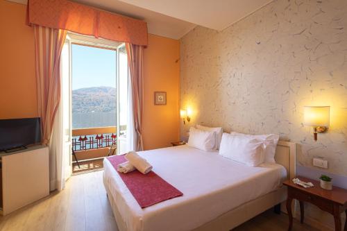 - une chambre avec un grand lit et une grande fenêtre dans l'établissement Hotel Pallanza by LVG Hotel Collection, à Verbania