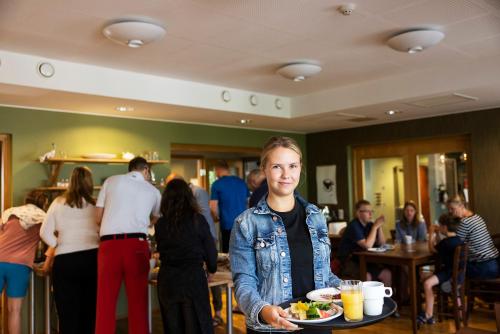 a woman holding a plate of food in a restaurant at Strandnäs Hotell in Mariehamn