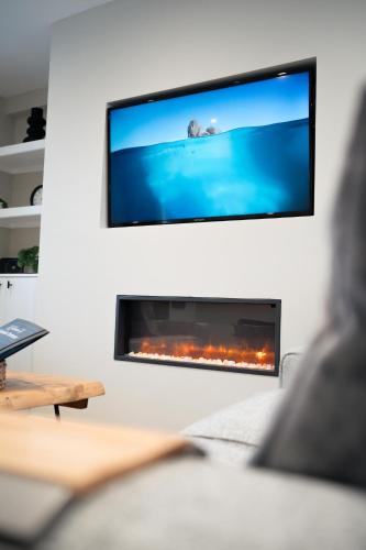 een persoon in een woonkamer met een tv boven een open haard bij Snowdonia Quarryman cottage in Llanberis