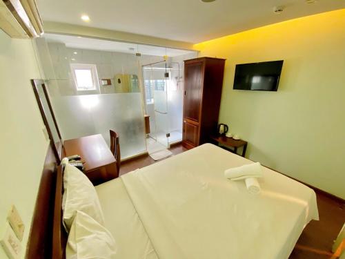 1 dormitorio con cama blanca y ducha en Art Deluxe Hotel, en Nha Trang