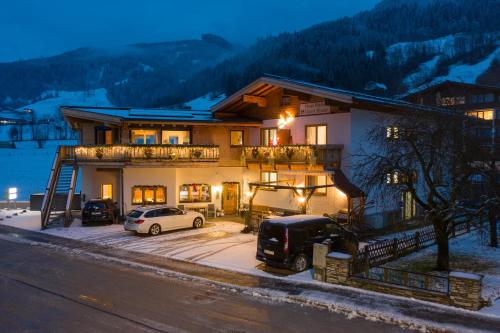 a house with two cars parked in front of it at Pension Patricia in Kaprun