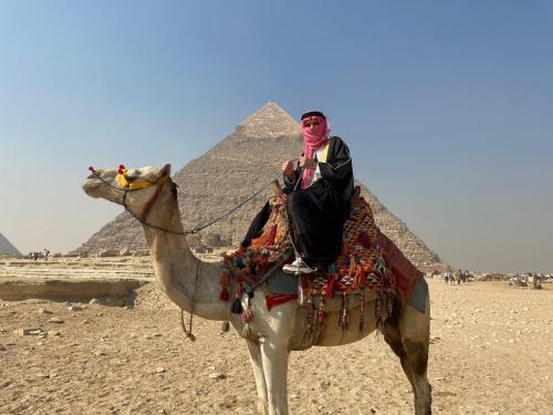 Un uomo che cavalca un cammello davanti alle piramidi di New pyramids way a Il Cairo