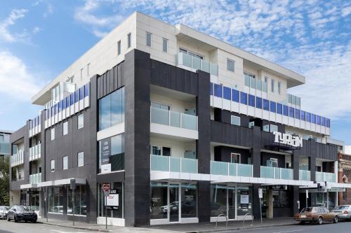 an apartment building on a street with cars parked in front at Tyrian Serviced Apartments Fitzroy in Melbourne