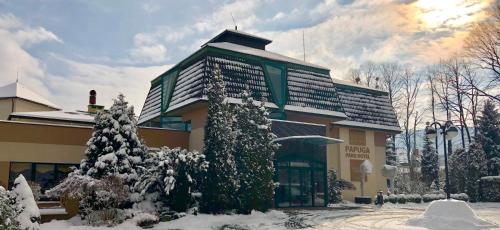 a building with snow covered trees in front of it at Papuga Park Hotel Wellness Marrakesz & SPA in Bielsko-Biala