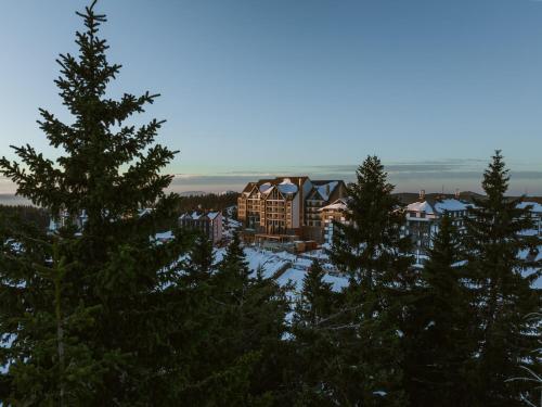 Blick auf ein Resort mit Schnee und Bäumen in der Unterkunft Viceroy Kopaonik Serbia in Kopaonik