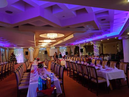 une salle de banquet avec de longues tables et chaises à éclairage violet dans l'établissement Hotel President, à Arad