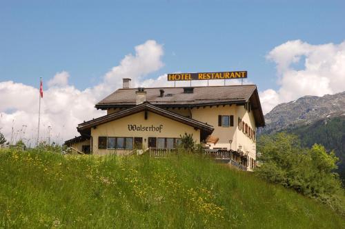 un hôtel avec un panneau au-dessus d'un bâtiment dans l'établissement Hotel Restaurant Walserhof, à Medels im Rheinwald