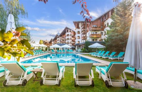 een zwembad in een hotel met stoelen en parasols bij Kempinski Hotel Grand Arena Bansko in Bansko