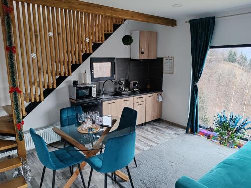 a kitchen and dining room with a table and blue chairs at Touch the Sky in Moieciu de Jos