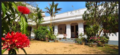 una casa bianca con alberi e fiori di fronte di Dutch Square Hostel a Alleppey