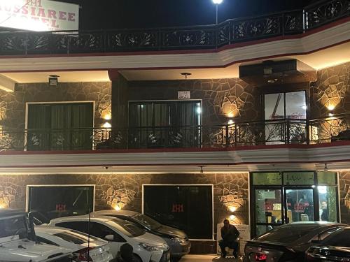 een gebouw waar 's nachts auto's buiten geparkeerd staan bij Mussiaree Hotel in Murree