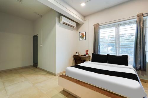 a bedroom with a large bed and a window at Hotel O ECR Stays Near Nemmeli Beach formerly GVS Homes in Chennai