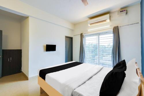 a bedroom with a large bed and a window at Hotel O ECR Stays Near Nemmeli Beach formerly GVS Homes in Chennai