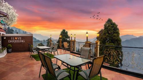 un ristorante con tavoli e sedie su un balcone con tramonto di Summit Grace Boutique Hotel & Spa a Darjeeling