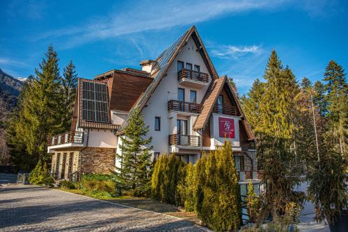 un grande edificio bianco con tetto in legno di Paj Hotelul Retreat & Spa a Sinaia