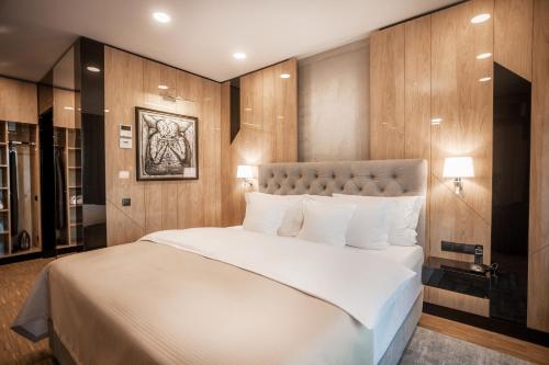 a bedroom with a large white bed with wooden walls at Hotel Platinia in Cluj-Napoca