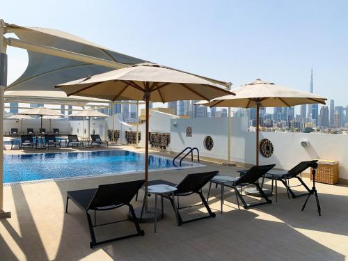 une terrasse avec des tables et des parasols ainsi qu'une piscine dans l'établissement Al Khoory Executive Hotel, Al Wasl, à Dubaï