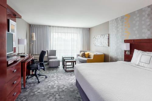 a hotel room with a bed and a desk and a chair at Courtyard by Marriott Kalamazoo Portage in Portage