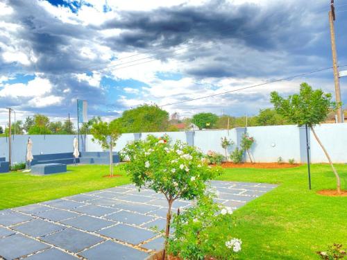 a garden with a stone walkway and a fence at PULA NALA LODGE in Rustenburg