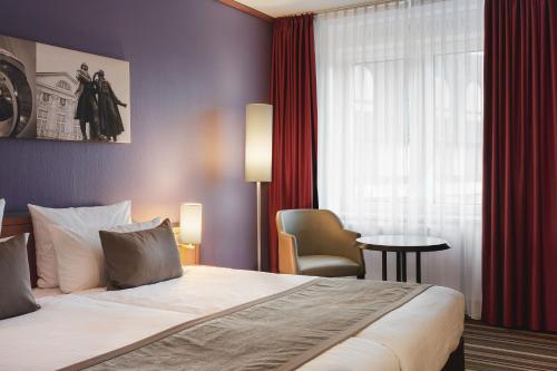 Habitación de hotel con cama, silla y ventana en Leonardo Hotel Weimar, en Weimar