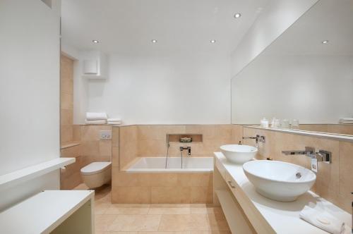 ein Badezimmer mit 2 Waschbecken und einer Badewanne in der Unterkunft Design-Boutique Hotel Vosteen in Nürnberg