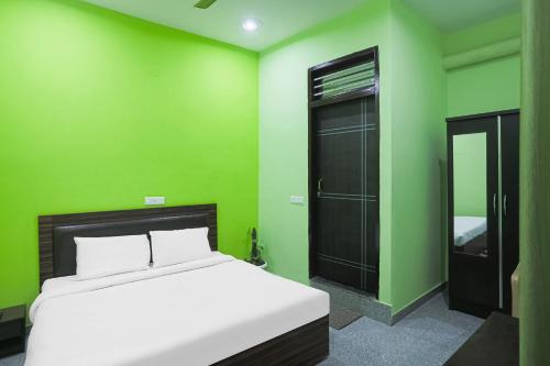 a bedroom with green walls and a bed and a mirror at Capital O A-one in Manesar