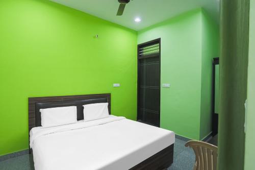 a green bedroom with a bed and a green wall at Capital O A-one in Manesar