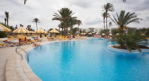 ein großer Pool mit Palmen und Stühlen in der Unterkunft Djerba Holiday Beach in Midoun