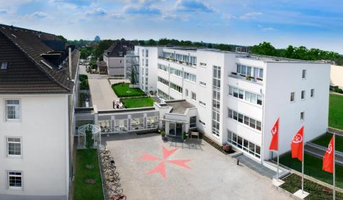 uma vista aérea de um edifício branco com duas bandeiras vermelhas em Johanniter Gästehaus em Münster