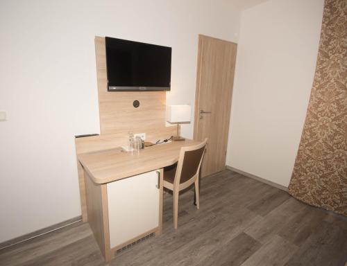 Cette chambre dispose d'un bureau et d'une télévision murale. dans l'établissement Hotel Sonne am Meer, à Norddeich