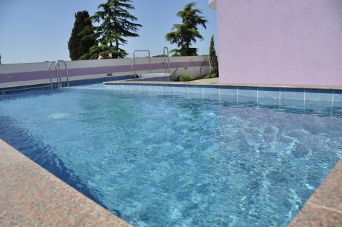 een zwembad met blauw water naast een roze gebouw bij Vila in Lavanda in Fažana