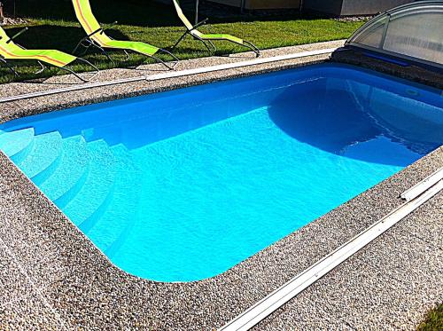 - une piscine bleue avec quelques chaises dans l'établissement Apartmány Vojta, à Telč