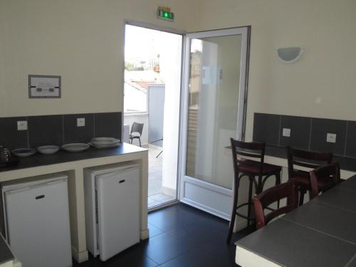 une cuisine avec une table et des chaises ainsi qu'une porte coulissante en verre. dans l'établissement Hôtel Belfort, à Montreuil