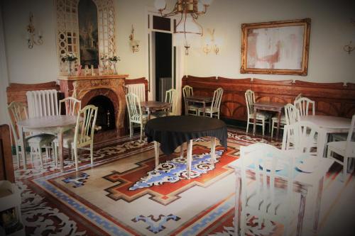 a room with white chairs and a table and a fireplace at Hotel El Xalet in Sitges