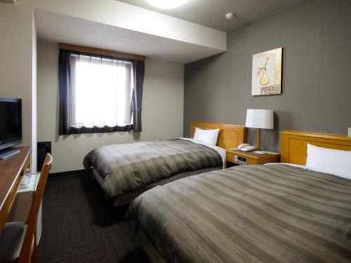 a hotel room with two beds and a television at Hotel Route-Inn Akita Tsuchizaki in Akita