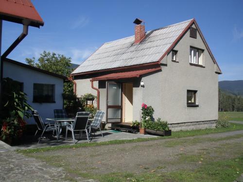 een klein wit huis met een tafel en stoelen bij Ubytování u Přadků in Čeladná