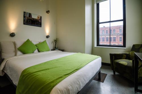 HI Boston Hostel في بوسطن: غرفة نوم بسرير وملاءات خضراء ونافذة