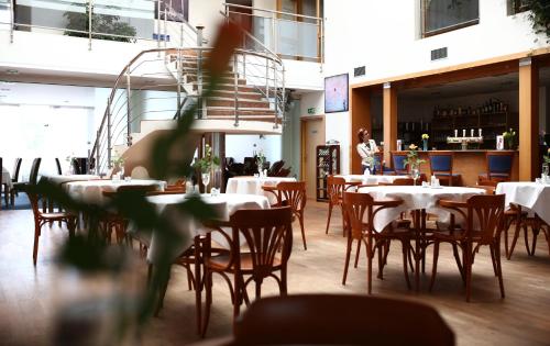 una sala da pranzo con tavoli e sedie e una persona sullo sfondo di Hotel Atrium a Vyškov