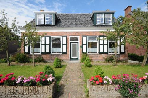 a brick house with flowers in the yard at Gastenverblijf Neeltje in Oostkapelle