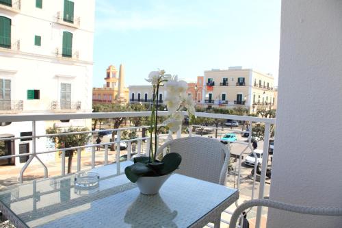 eine Vase mit einer Blume auf dem Tisch auf dem Balkon in der Unterkunft Hotel Città Bella in Gallipoli