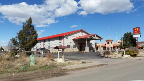 a large white building with a red roof next to a road at 9 Motel in Fort Collins