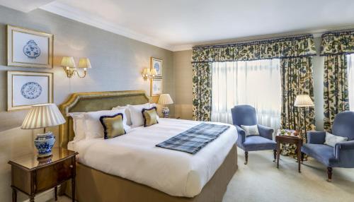 um quarto de hotel com uma cama grande e duas cadeiras em The Stafford London em Londres