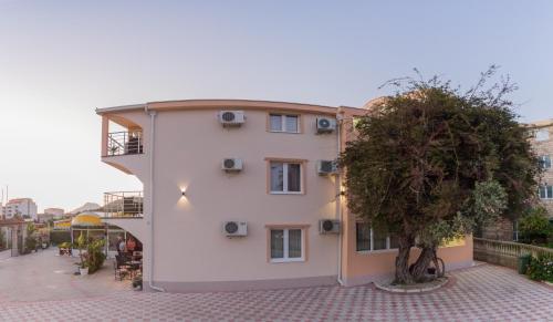 un edificio blanco con un árbol delante en Villa Jadran Apartments, en Bar