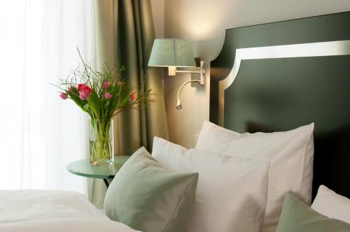 un vase de fleurs sur une table à côté d'un lit dans l'établissement Hotel im Hof, à Munich