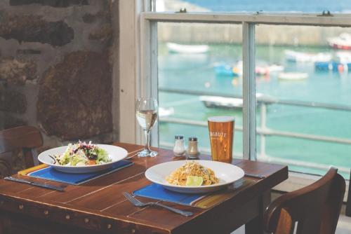 una tavola con due piatti di cibo e un bicchiere di vino di The Ship Inn a Mousehole