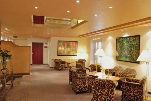 a lobby with chairs and tables in a hotel at Hotel Maack in Seevetal